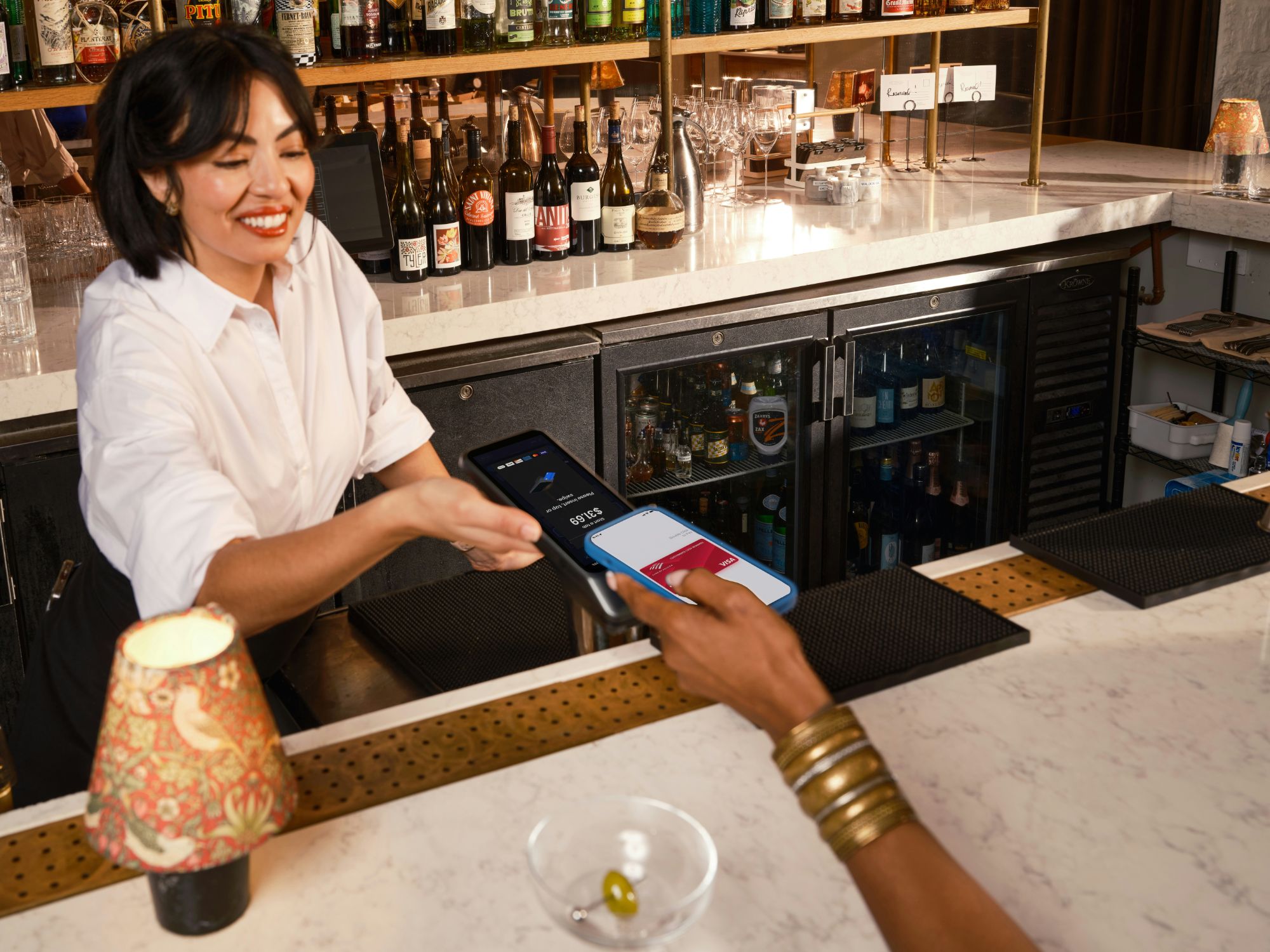 Cliente activant un tampon de fidélité en tapant son téléphone sur la plaque NFC Klapp posée au comptoir