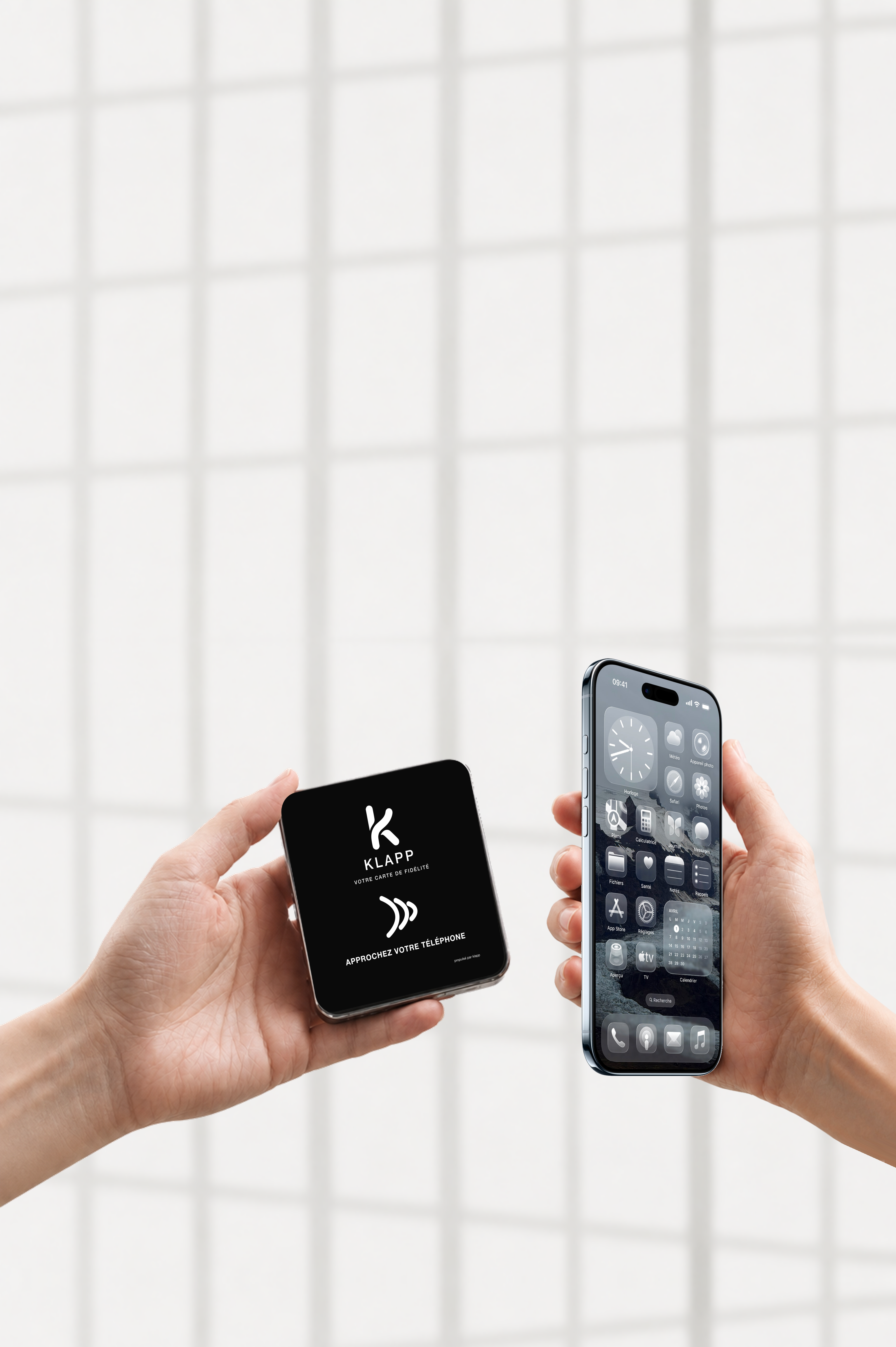 Deux mains présentent une plaque KLAPP et un iPhone devant de grandes fenêtres.